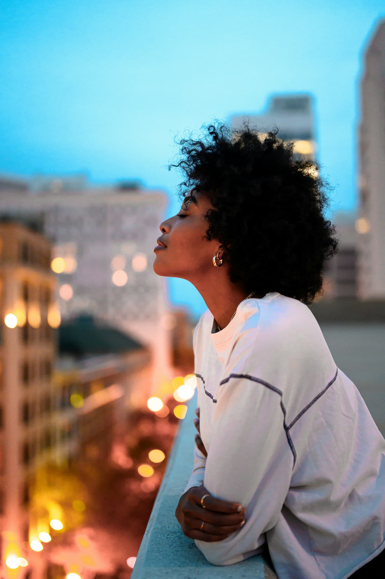 Une jeune femme regarde la ville au crépuscule